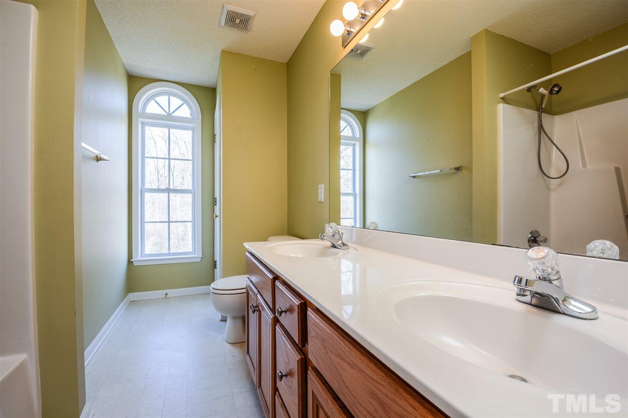 8413 Ridgebury Road Raleigh, NC 27603 - Photo 16 of 18 a bathroom with a granite countertop sink a toilet and a large mirror