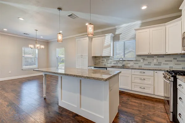 a large kitchen with cabinets wooden floor and a sink