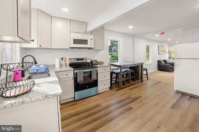 a kitchen with stainless steel appliances granite countertop wooden cabinets a stove a sink and a wooden floor