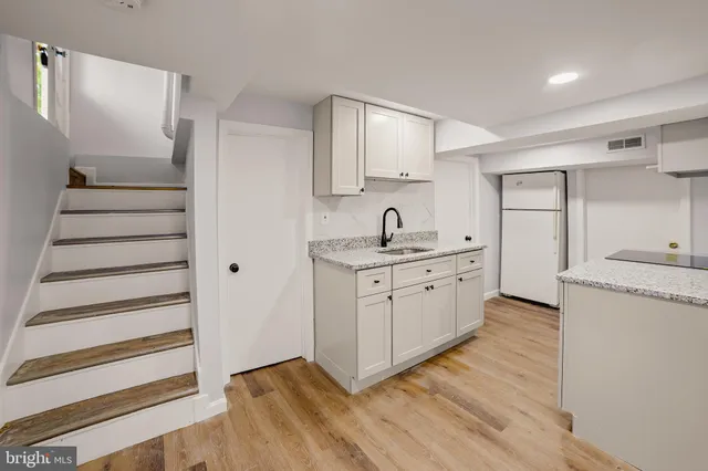 a kitchen with white cabinets and sink