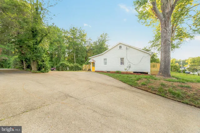a view of a white house with a yard and large trees