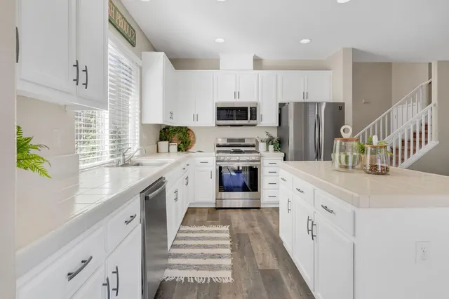 a kitchen with stainless steel appliances a stove a sink a refrigerator a counter top space and cabinets