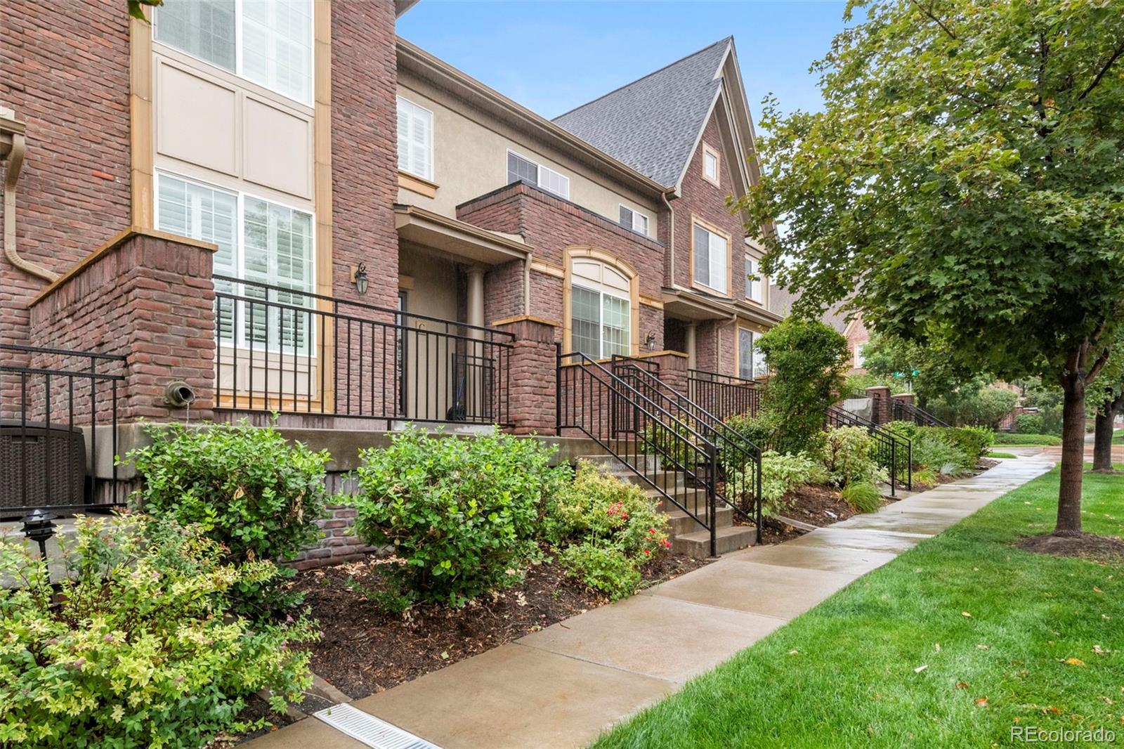 a view of a brick house with a yard and plants