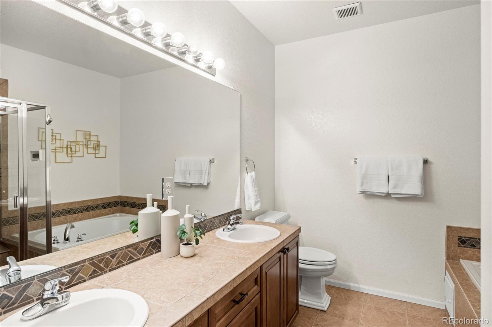 592 Brookhurst Avenue, Unit 26C Highlands Ranch, CO 80129 - Photo 24 of 30 a bathroom with a granite countertop sink a toilet a mirror and bathtub