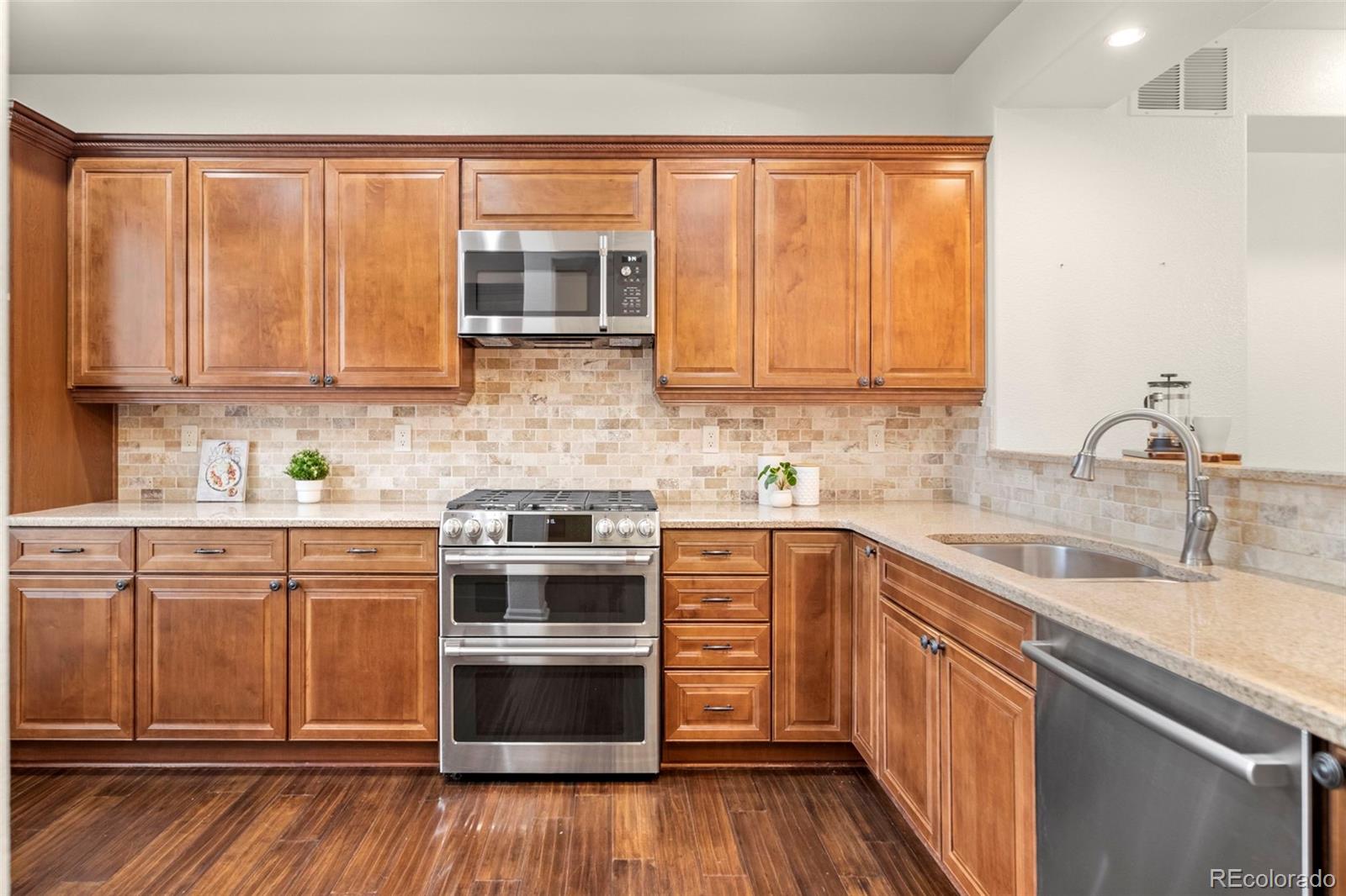 592 Brookhurst Avenue, Unit 26C Highlands Ranch, CO 80129 - Photo 5 of 30 a kitchen with stainless steel appliances granite countertop wooden cabinets a sink and a stove
