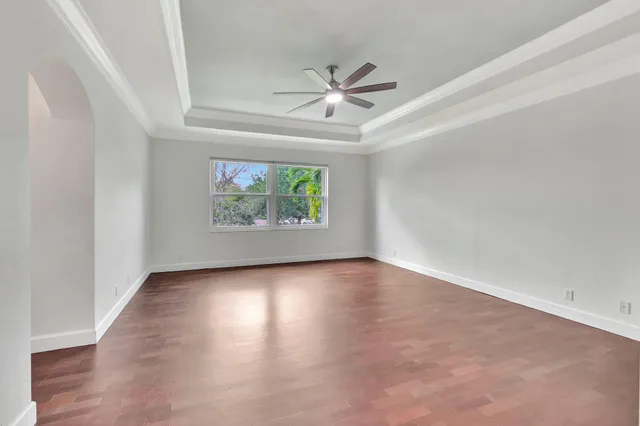 an empty room with window ceiling fan and wooden floor