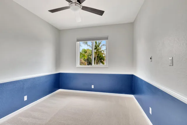 a view of an empty room with chandelier fan