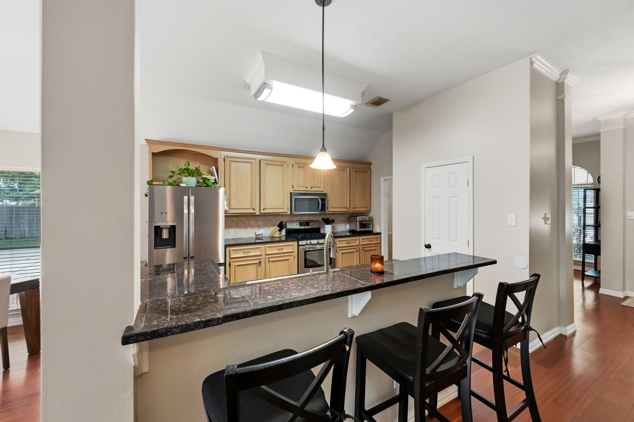 7514 Tumbling Road Humble, TX 77346 - Photo 10 of 28 a kitchen with stainless steel appliances kitchen island granite countertop a table chairs in it and wooden floors