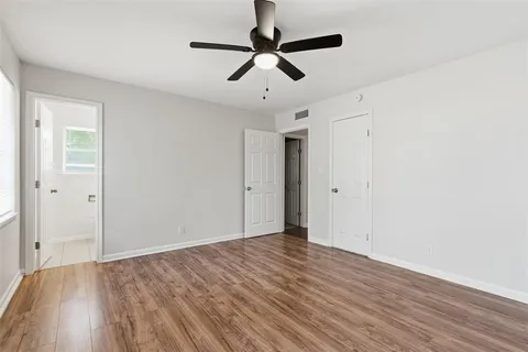 an empty room with windows and fan