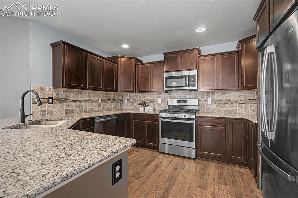 4467 Hessite Loop Colorado Springs, CO 80938 - Photo 12 of 37 a kitchen with stainless steel appliances granite countertop a sink stove and refrigerator