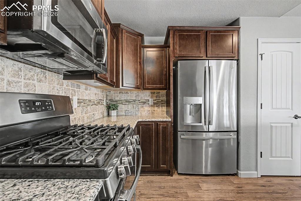 4467 Hessite Loop Colorado Springs, CO 80938 - Photo 13 of 37 a kitchen with stainless steel appliances granite countertop a refrigerator a sink and wooden cabinets