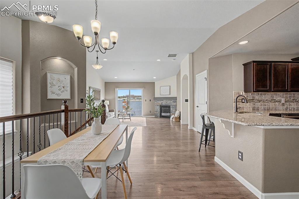 4467 Hessite Loop Colorado Springs, CO 80938 - Photo 10 of 37 a dining room with wooden floor a chandelier a wooden table and chairs