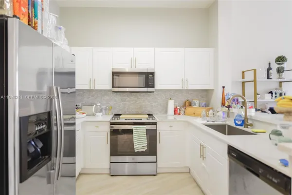 a kitchen with stainless steel appliances a white refrigerator a sink a stove a microwave and cabinets
