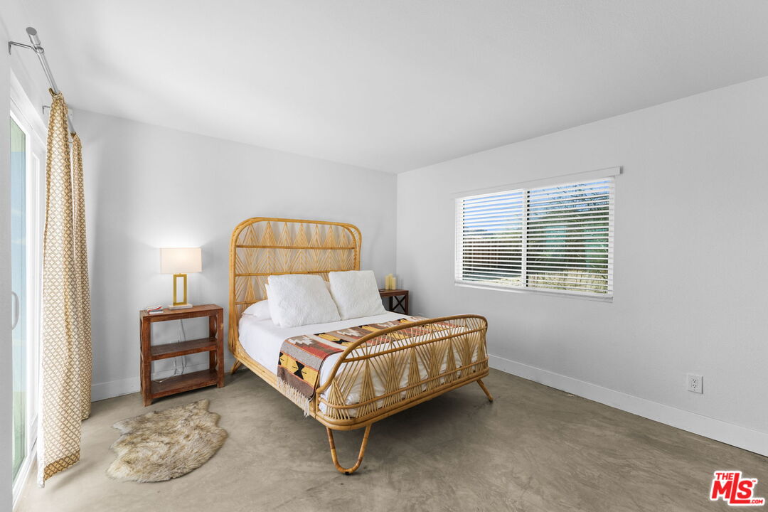 4789 Avenida Del Sol Joshua Tree, CA 92252 - Photo 13 of 37 a bedroom with a bed lamp and a window
