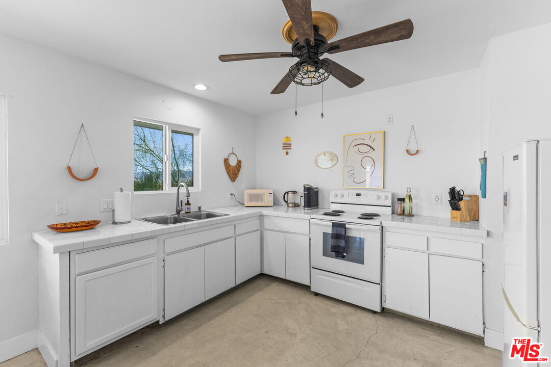 4789 Avenida Del Sol Joshua Tree, CA 92252 - Photo 8 of 37 a kitchen with stainless steel appliances granite countertop cabinets and window
