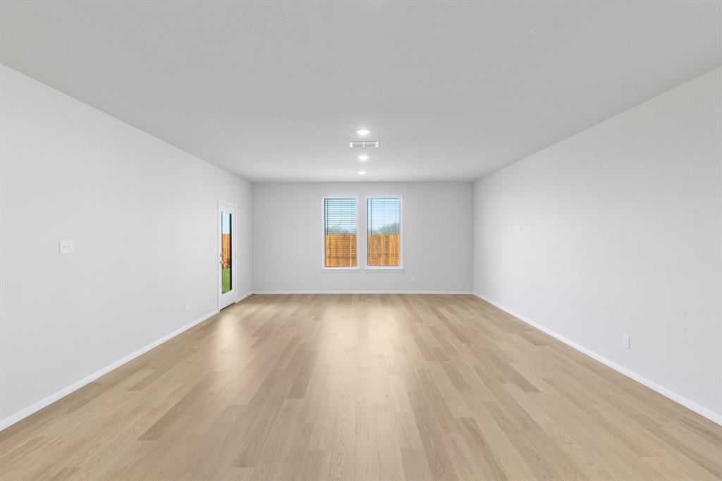 7628 Kingfisher Road Aubrey, TX 76227 - Photo 12 of 34 an empty room with wooden floor and windows