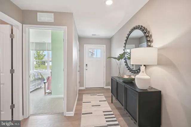 a hallway with white doors wooden floor and front door
