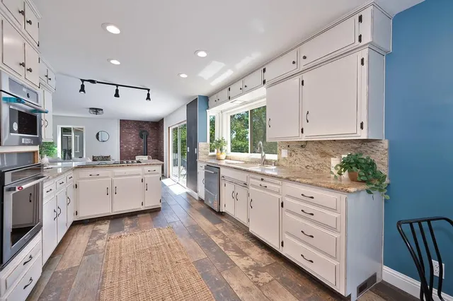 a large kitchen with stainless steel appliances granite countertop a lot of counter space and wooden floors