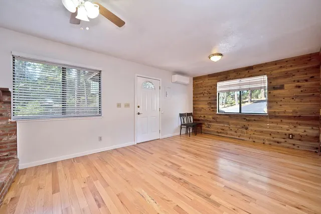 a view of an empty room with wooden floor and a window