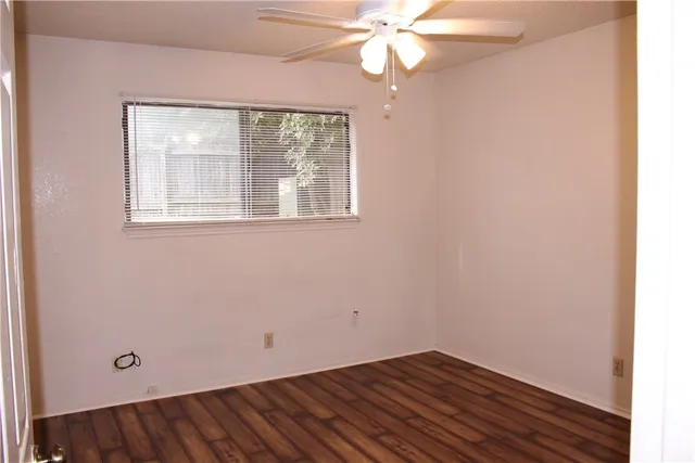 an empty room with a window and a fan