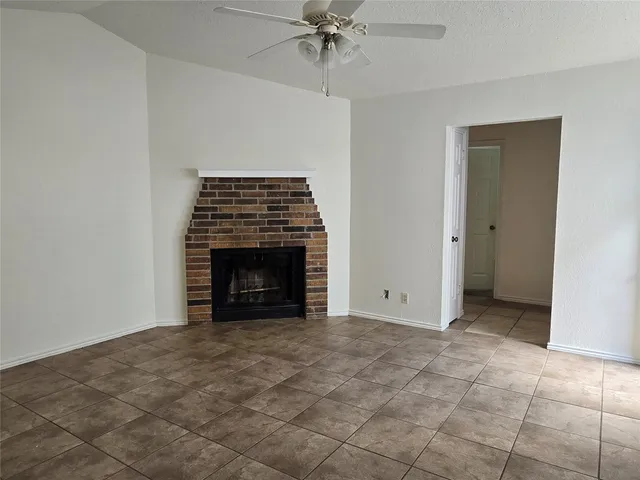 an empty room with a fireplace and a chandelier fan
