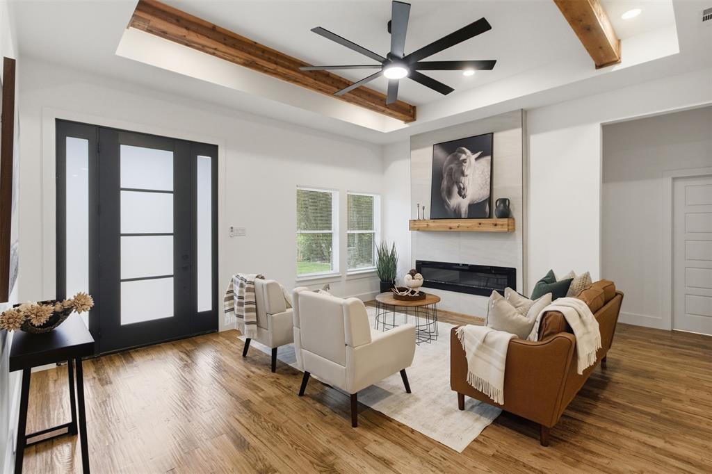 429 Waterboard Road Trinidad, TX 75163 - Photo 8 of 25 Spacious living area featuring wood-finish flooring, a modern linear fireplace with a light-toned tile surround, and an exposed beam ceiling
