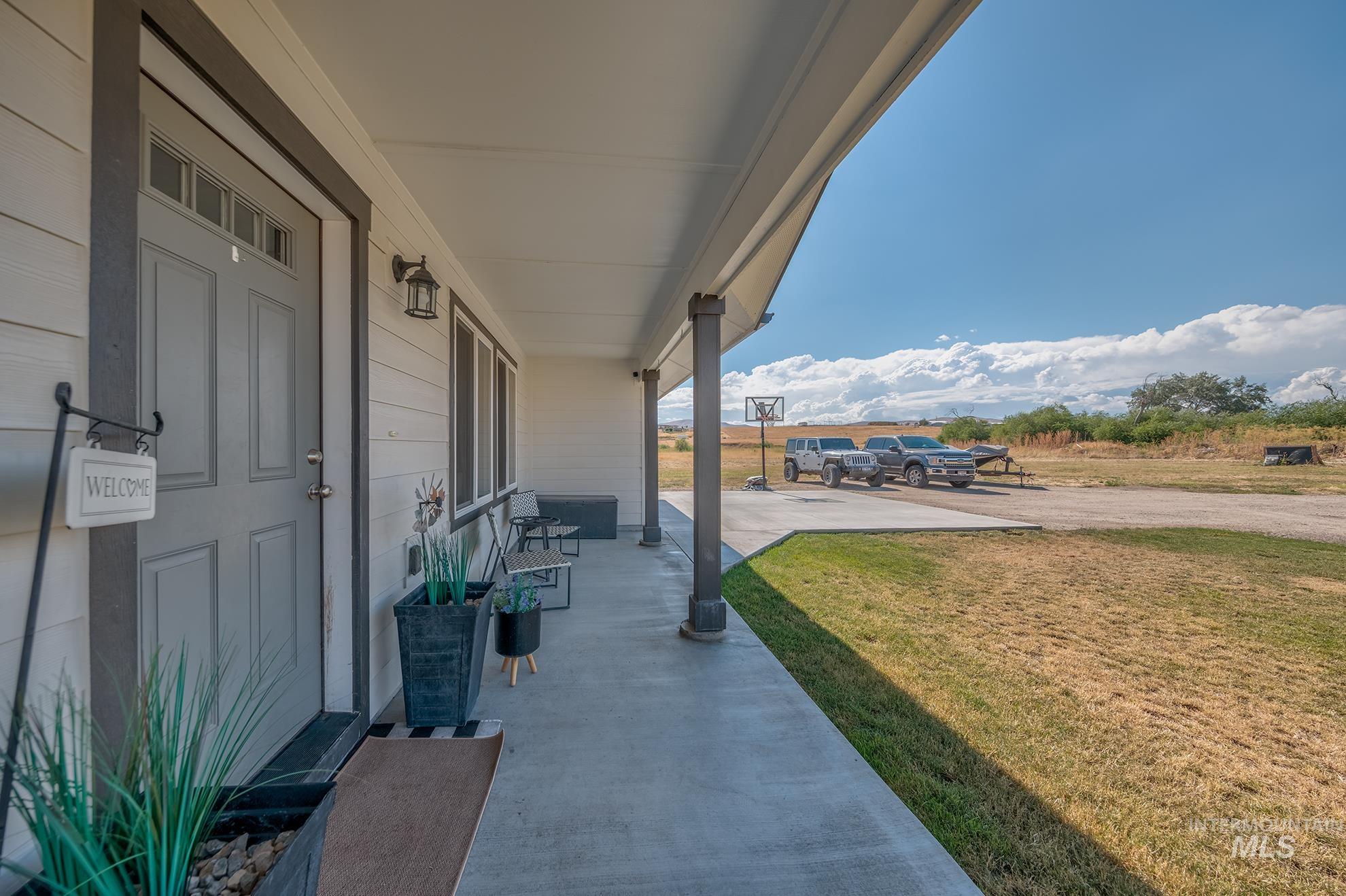 1049 Price Road Weiser, ID 83672 - Photo 3 of 47 Covered porch featuring a paneled entry door with transom window, exterior lighting fixture, and horizontal siding