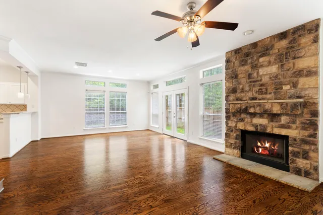 a view of an empty room with wooden floor fireplace and a window