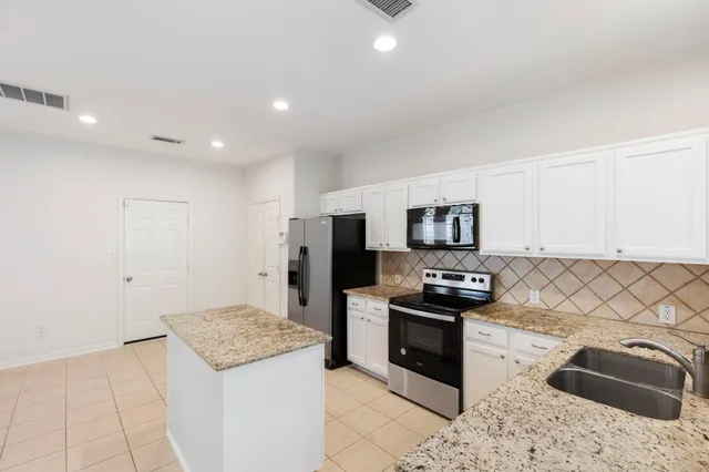 a kitchen with granite countertop a refrigerator and a stove top oven