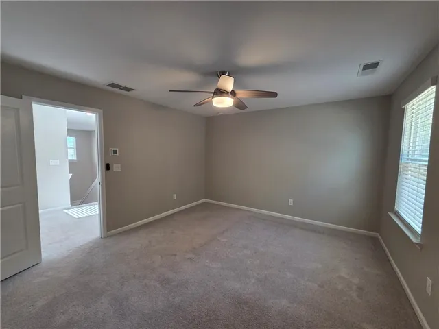 en empty room with windows and chandelier fan