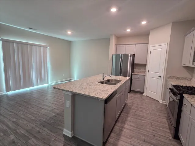 a kitchen with stainless steel appliances granite countertop a refrigerator a stove and a wooden floors