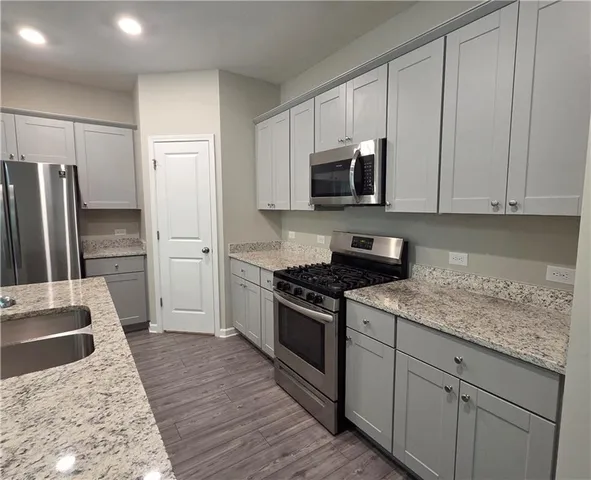 a kitchen with stainless steel appliances granite countertop a stove a refrigerator and a sink