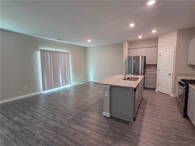 a view of kitchen with stainless steel appliances granite countertop a stove top oven a sink and a refrigerator