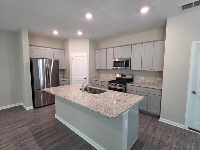 a kitchen with a refrigerator a microwave a sink and cabinets