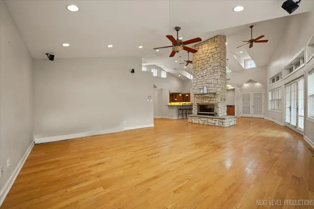 a big room with wooden floor a ceiling fan and windows