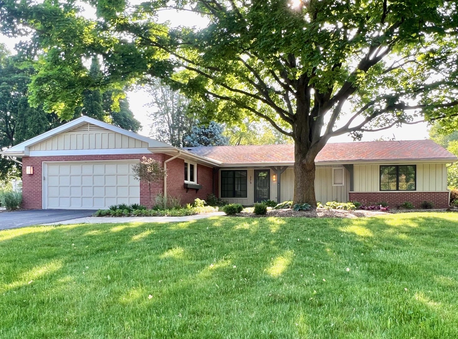 a front view of a house with a garden and trees