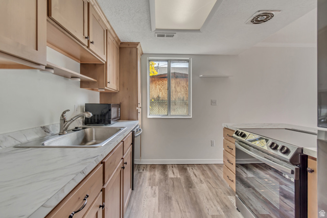 653 South 500 West, Unit 1 Provo, UT 84601 - Photo 8 of 17 Kitchen featuring wood-finish cabinetry, stainless steel sink, a stainless steel range, light-toned countertops, and wood-finish flooring