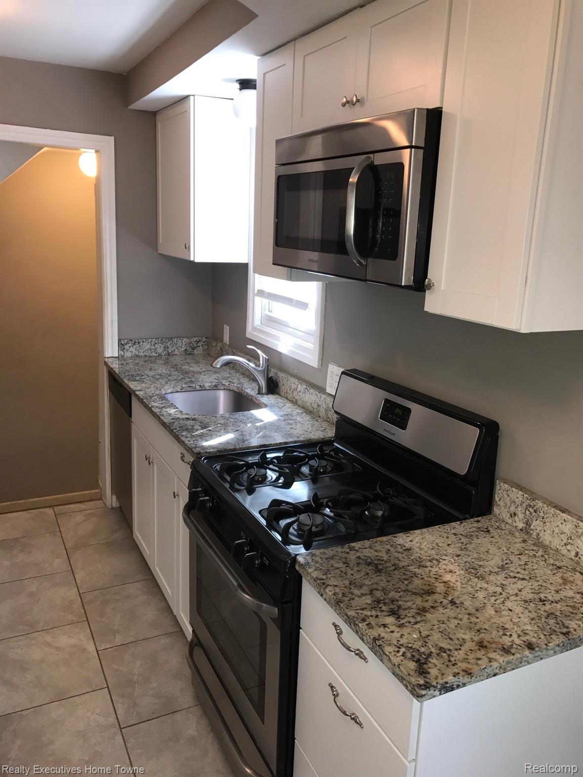 2427 Cambridge Road Berkley, MI 48072 - Photo 6 of 17 Kitchen featuring white cabinetry, speckled granite countertops, stainless steel appliances, and large format tile flooring