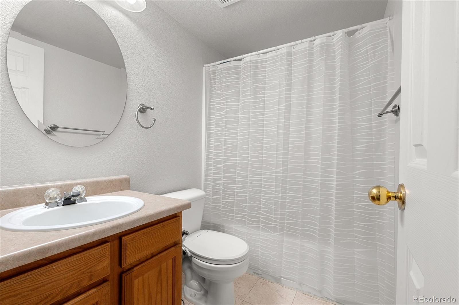 3828 South Rome Way Aurora, CO 80018 - Photo 12 of 19 a bathroom with a sink toilet and mirror