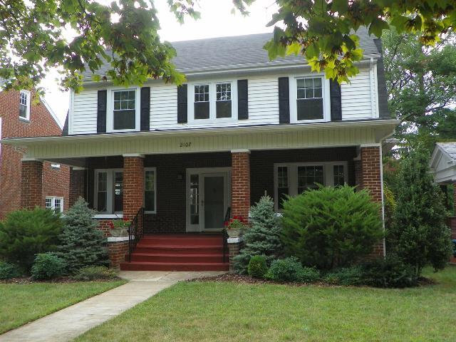 a front view of a house with garden and trees