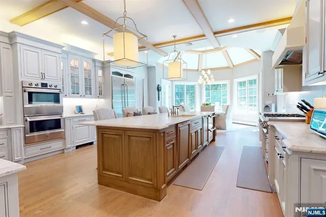 a large kitchen with kitchen island a large window a sink and stainless steel appliances