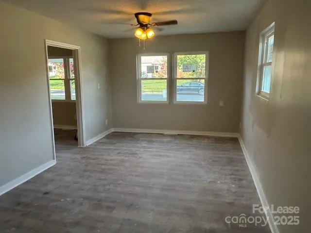 an empty room with windows and fan