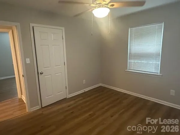 an empty room with wooden floor cabinet and windows
