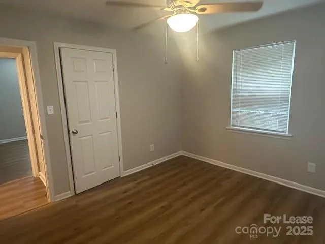 an empty room with wooden floor cabinet and windows