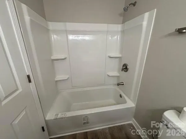 a white bath tub sitting next to a white toilet and vanity