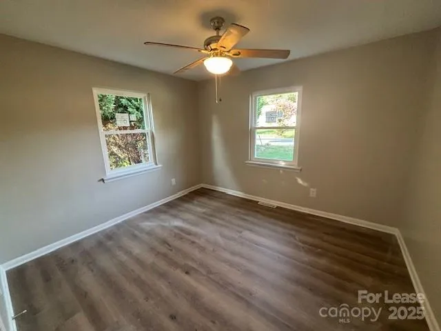 a view of an empty room and window and chandelier fan