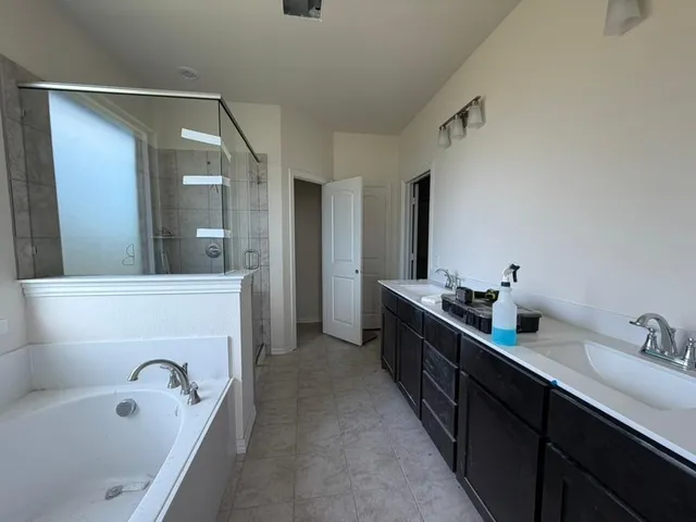 a bathroom with a tub sink double vanity granite tub shower and mirror