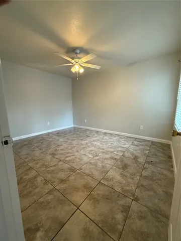 an empty room with a chandelier fan and windows
