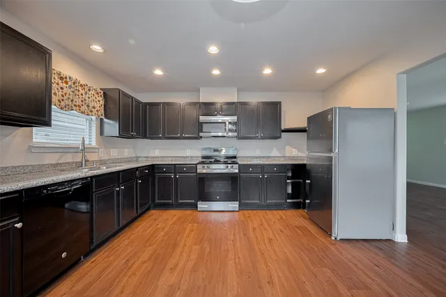 a large kitchen with stainless steel appliances granite countertop a sink a stove a refrigerator and a microwave