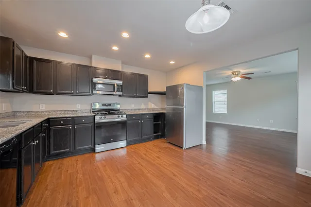 a kitchen with stainless steel appliances granite countertop a refrigerator a sink dishwasher a stove and a microwave oven on granite countertops